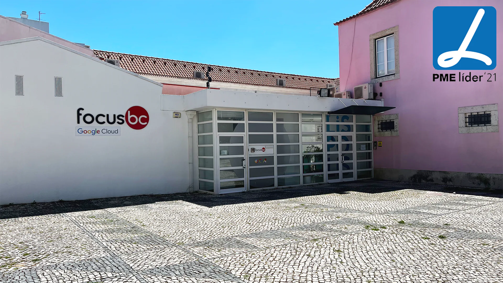 Exterior of the Focus BC office with Google Cloud branding on a white wall, glass entrance doors, and a “PME Líder ’21” award badge displayed in the top corner.