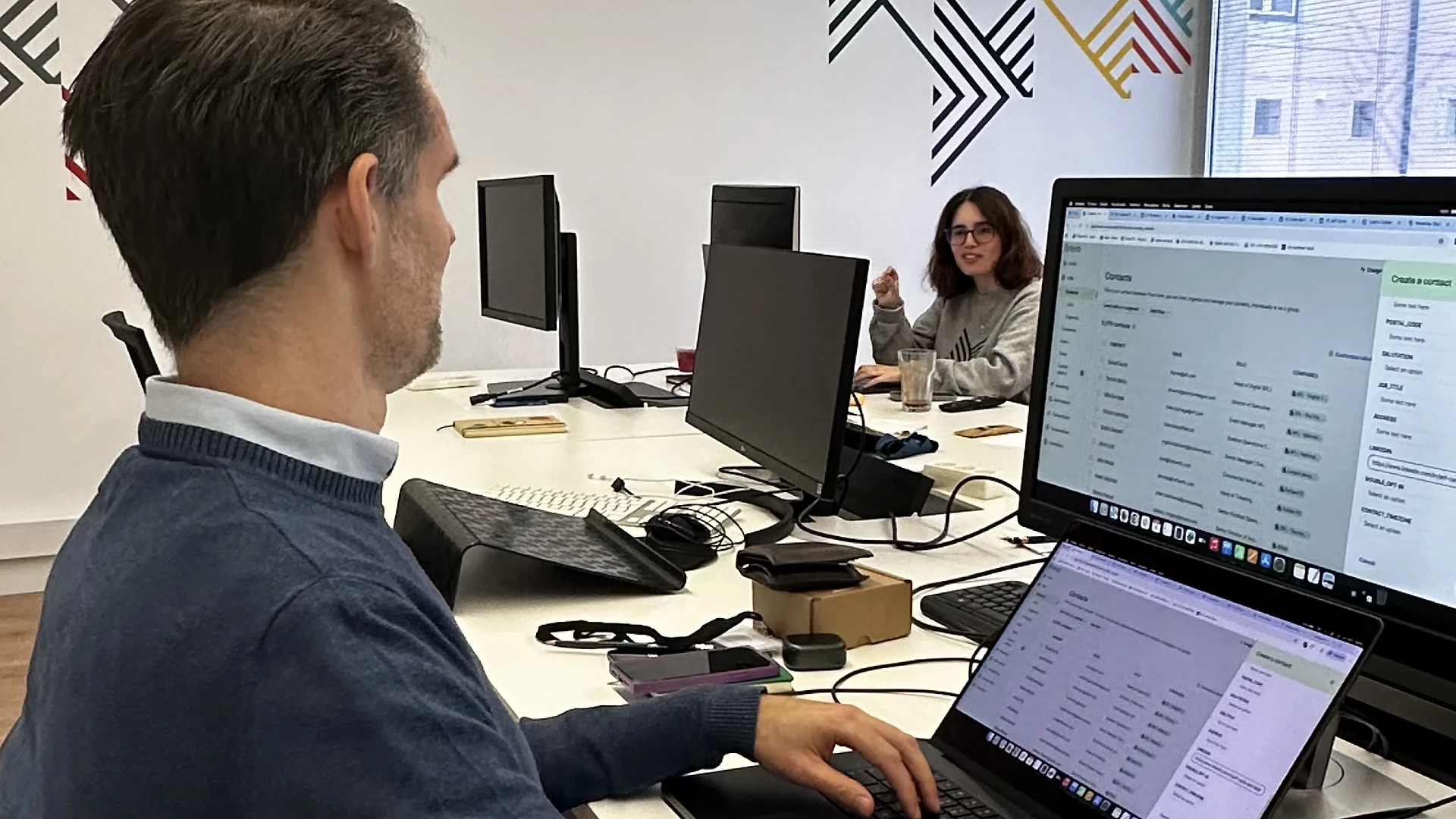 Joana smiling in a portrait against a white wall with a purple graphic detail.