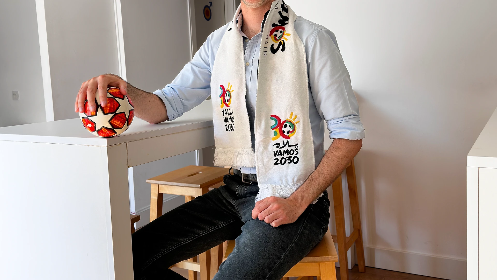 Joana smiling in a portrait against a white wall with a purple graphic detail.