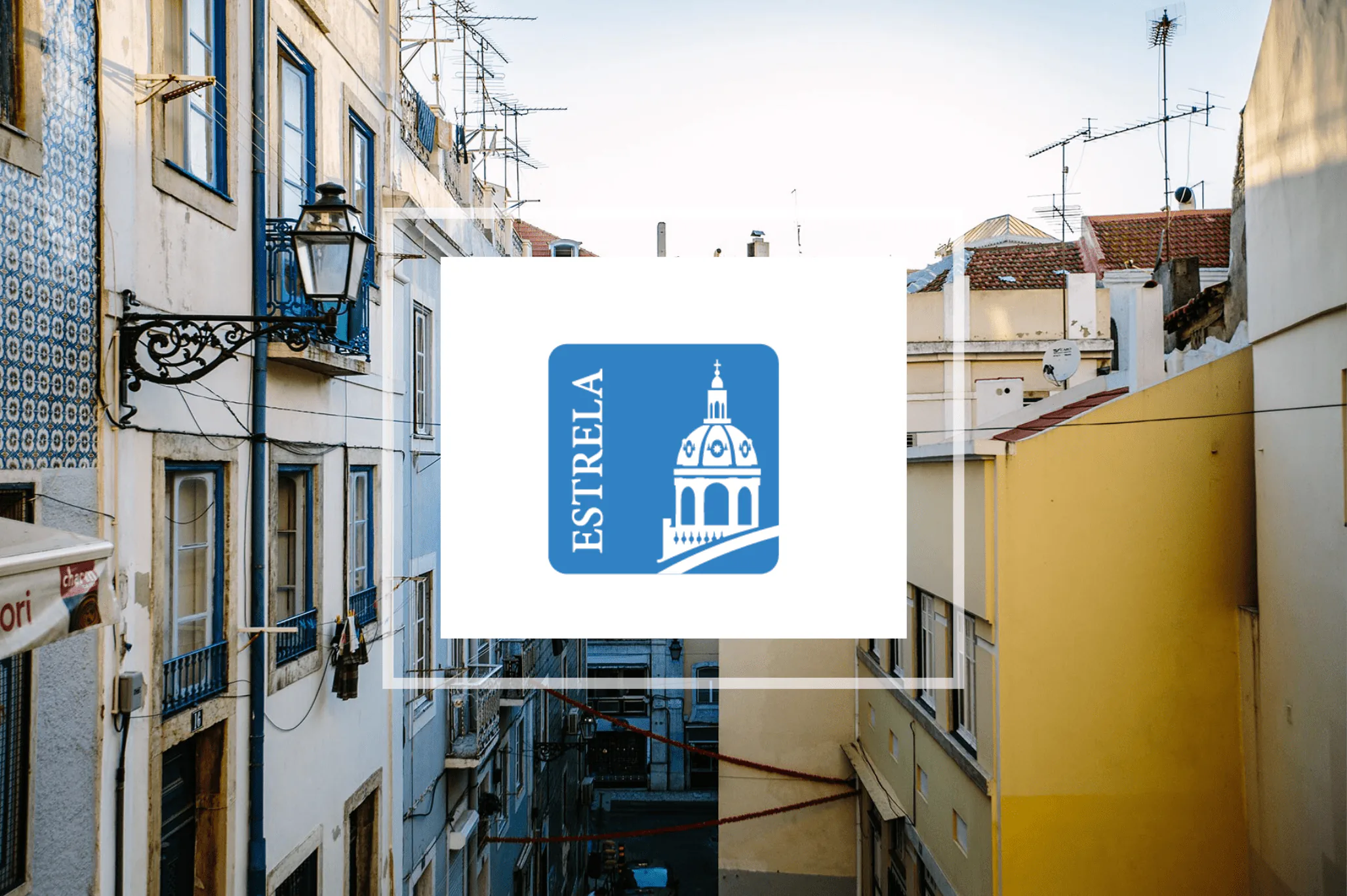 Estrela parish logo overlaid on a Lisbon street scene with traditional tiled façades and colorful buildings.
